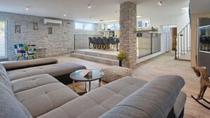 A spacious living area with a stone wall, a dining area with chairs, a staircase, and a dog statue. - Vacation home La Mer by Interhome (Pula)