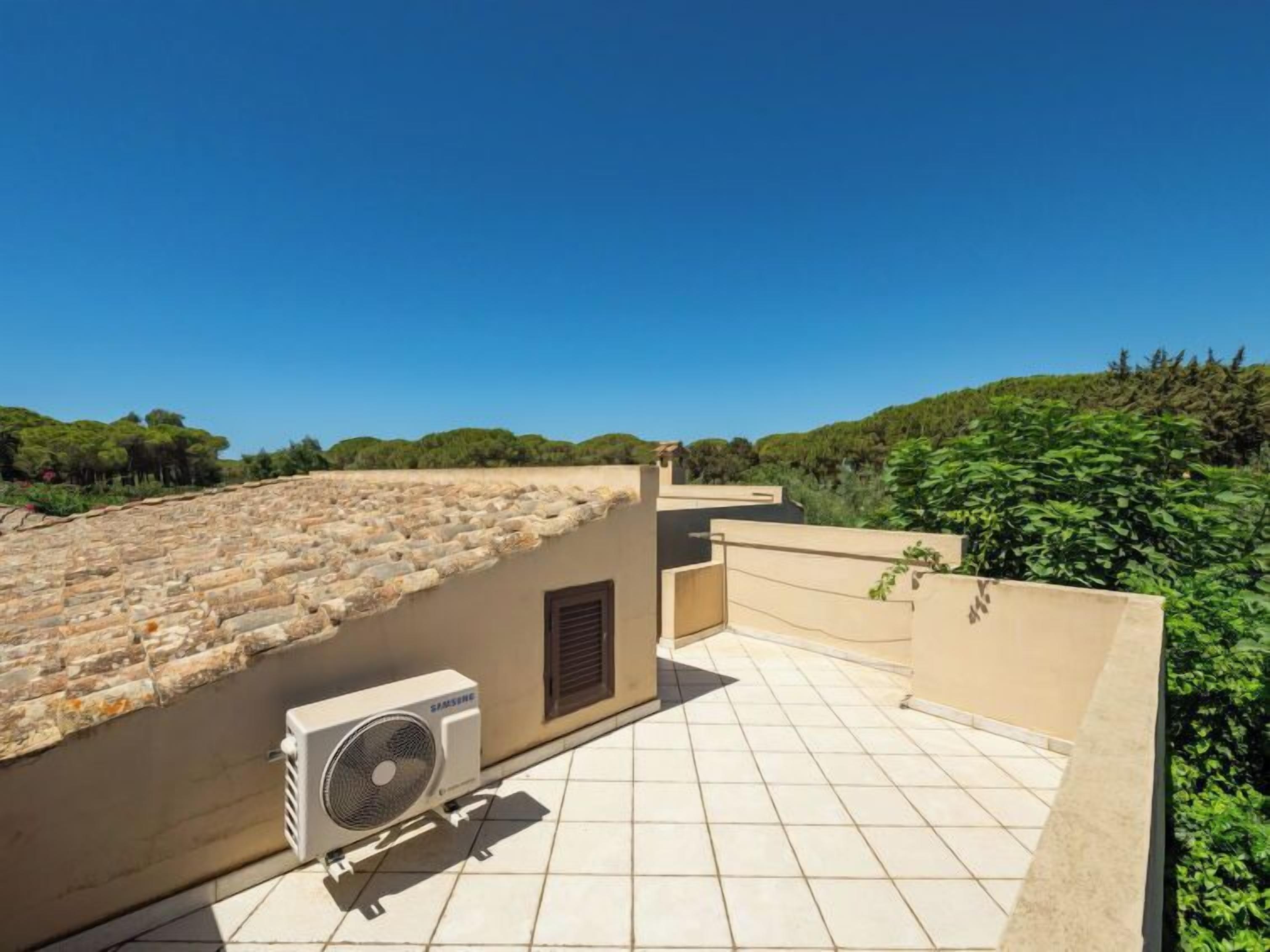 Una terraza en la azotea con paredes de piedra, un equipo de aire acondicionado Samsung y piso de baldosas.