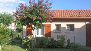 A house with a tiled roof, a garden with potted plants, and a small tree with pink flowers. - Bosquet aux Ecureuils by Interhome (Capbreton)