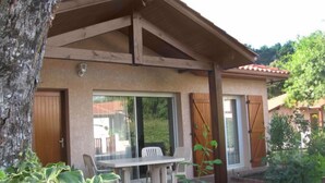 A covered patio with a table and chairs, a wooden door, and a window with shutters. - Bosquet aux Ecureuils by Interhome (Capbreton)