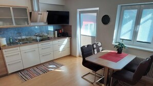 A modern kitchen with white cabinets, a built-in oven, and a flat-screen TV. - Rupertus by Interhome (Zell am See)