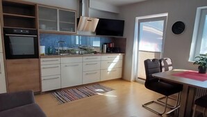 A modern kitchen with white cabinets, a built-in oven, and a stainless steel range hood. - Rupertus by Interhome (Zell am See)