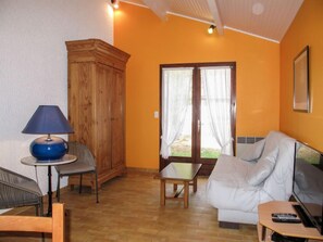 Una sala de estar acogedora con un mueble de madera, una lámpara azul, un sofá blanco y una pequeña mesa.
