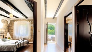 Quarto com cama, parede de pedra e vista para uma varanda.