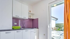 Una cocina moderna con armarios blancos, un salpicadero morado y un escurreplatos verde.
