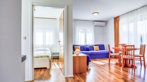 Una sala moderna con un sofá azul, mesa de comedor de madera y sillas.