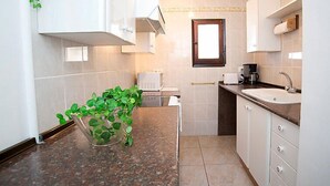 Een kleine keuken met een spoelbak, aanrecht en een raam.