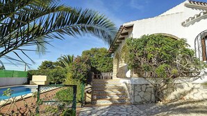 Un espace piscine agrémenté d’un escalier en pierre menant à un bâtiment blanc doté d’un mur en pierre et d’un portail en métal.