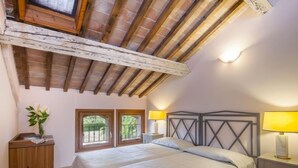 Ein Schlafzimmer mit zwei Betten, Holzbalken an der Decke, einem Nachttisch mit Lampe und einem Fenster mit Blick.