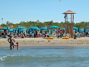 A beach with umbrellas, a lifeguard tower, and people enjoying the water.