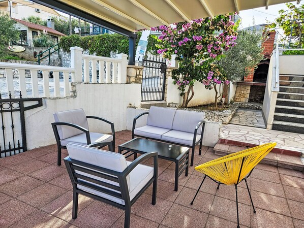 Un espacio al aire libre con dos sofás y una mesa, una silla amarilla y vistas a un edificio con un letrero.