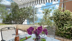 Un espace de restauration en plein air avec une table dressée pour deux personnes, une bouteille de vin et un vase rempli de fleurs violettes.