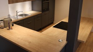 A modern kitchen with wooden cabinets, a stainless steel sink, and a black stove.