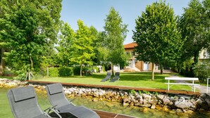 Eine Holzterrasse mit Liegestühlen und einem kleinen Teich mit Steinen.