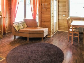 A cozy room with a curved sofa, a dining table, and a large rug.
