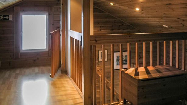 Un intérieur en bois avec un escalier, une fenêtre et un banc en bois.