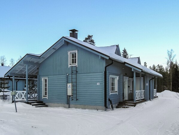 Une maison bleue à deux étages, dotée d’un porche, d’une cheminée et surplombant un paysage enneigé.