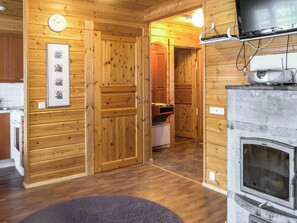 Un interior de madera con chimenea, un reloj y una foto enmarcada en la pared.
