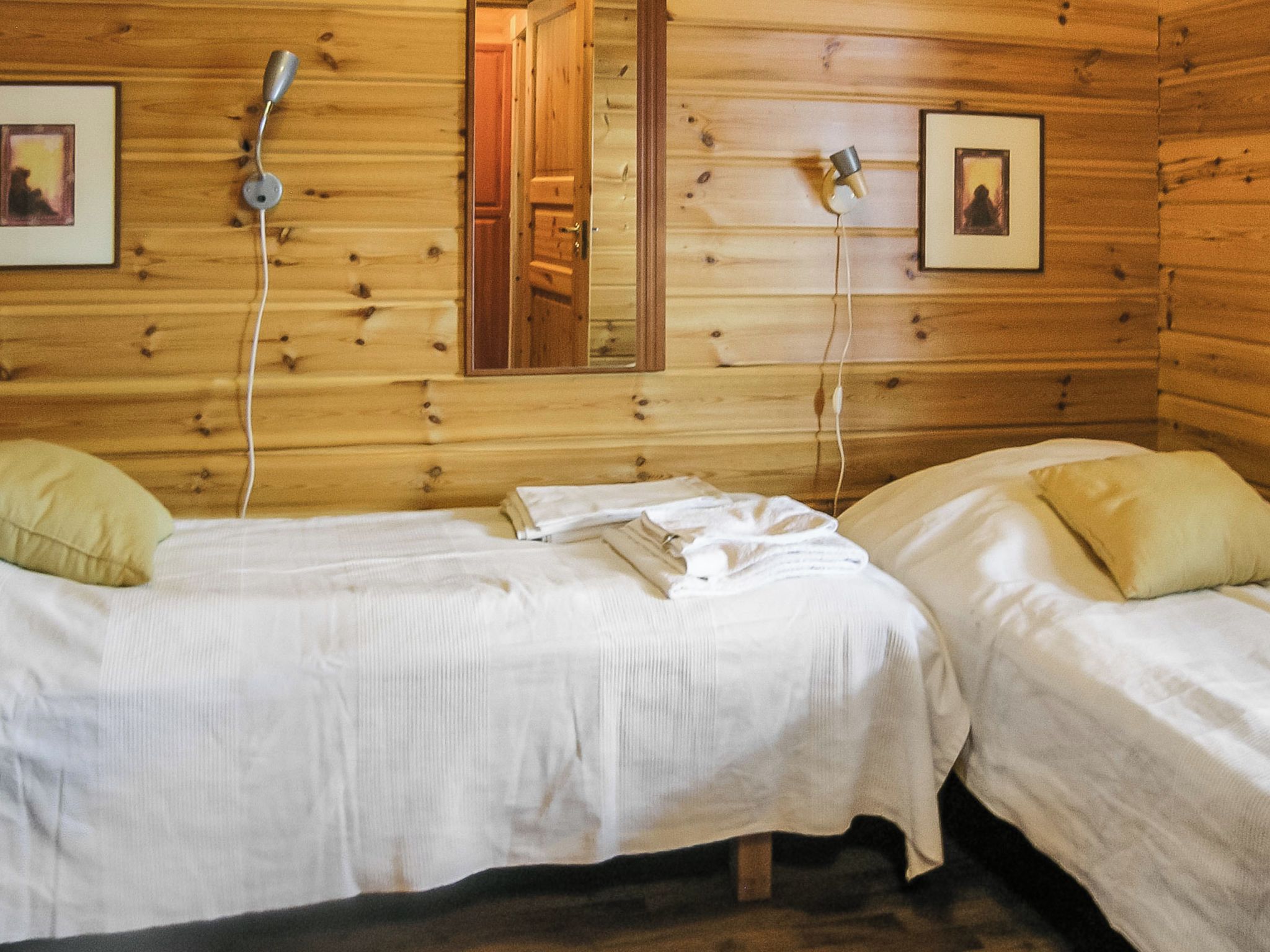 Una cabina con due letti singoli, pareti in legno e uno specchio.