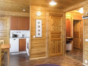 Un intérieur en bois comprenant une cuisine, un coin repas et un couloir menant à une autre pièce.