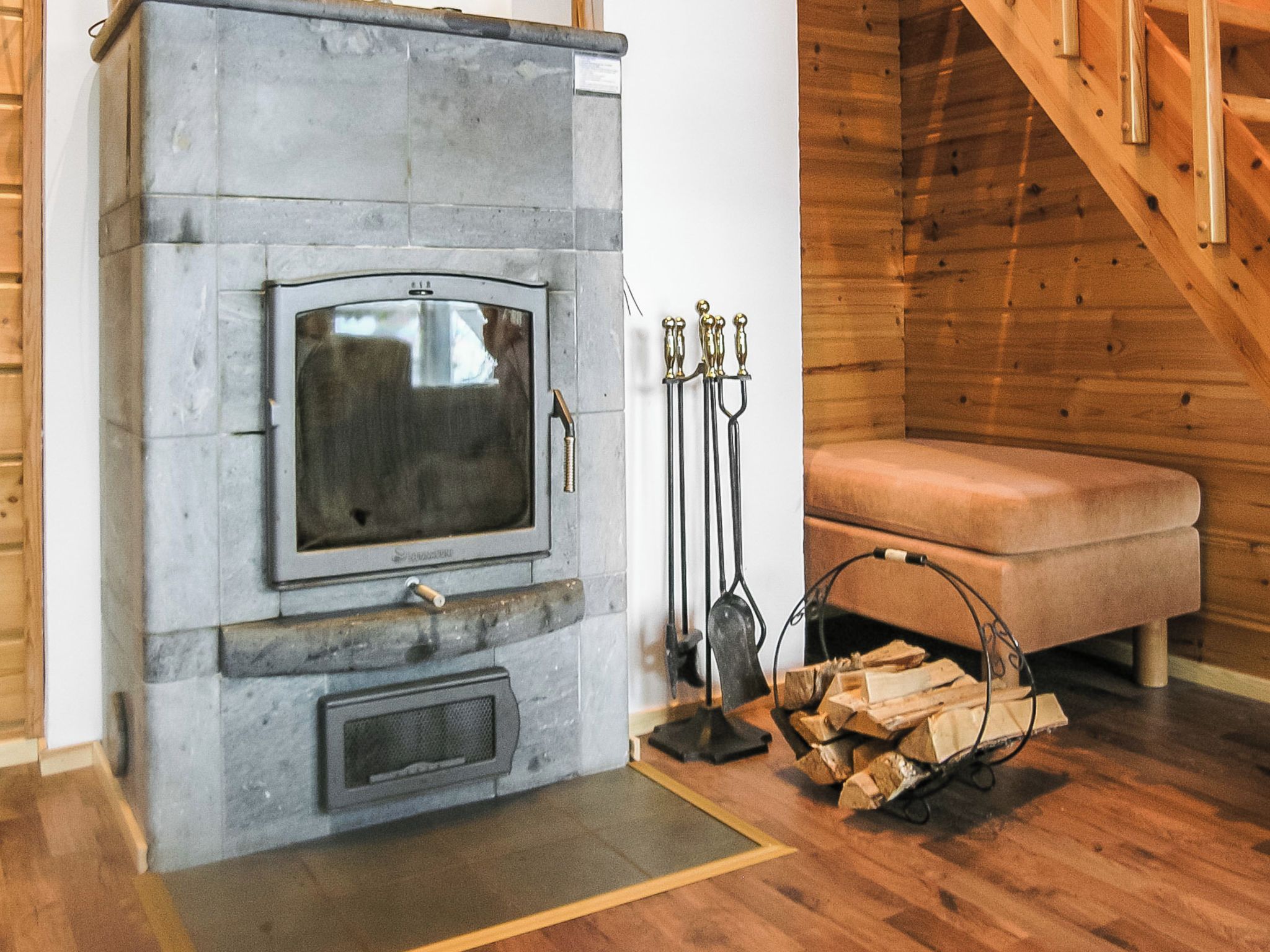 A stone fireplace with a television, a bench, and a firewood rack.