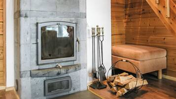 A stone fireplace with a television, a bench, and a firewood rack.