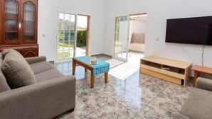 Una sala de estar con un sofá, una mesa de centro, un televisor y un mueble aparador.