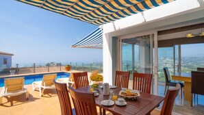 A terrace with a pool, dining table, chairs, and a large umbrella. - Stuttgart by Interhome (Moraira)