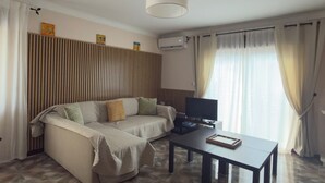 Ein Wohnzimmer mit einer Couch, einem Fernseher, einem Couchtisch und einer Deckenleuchte.
