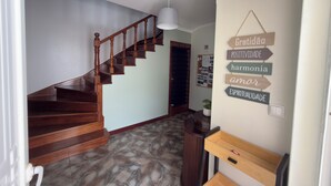 Eine Holztreppe führt zu einer Zwischenebene mit einem an der Wand befestigten Schild, das motivierende Sprüche zeigt.