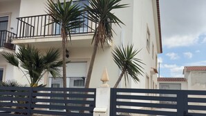 Ein zweistöckiges Gebäude mit Balkon, Tor und Palmen.