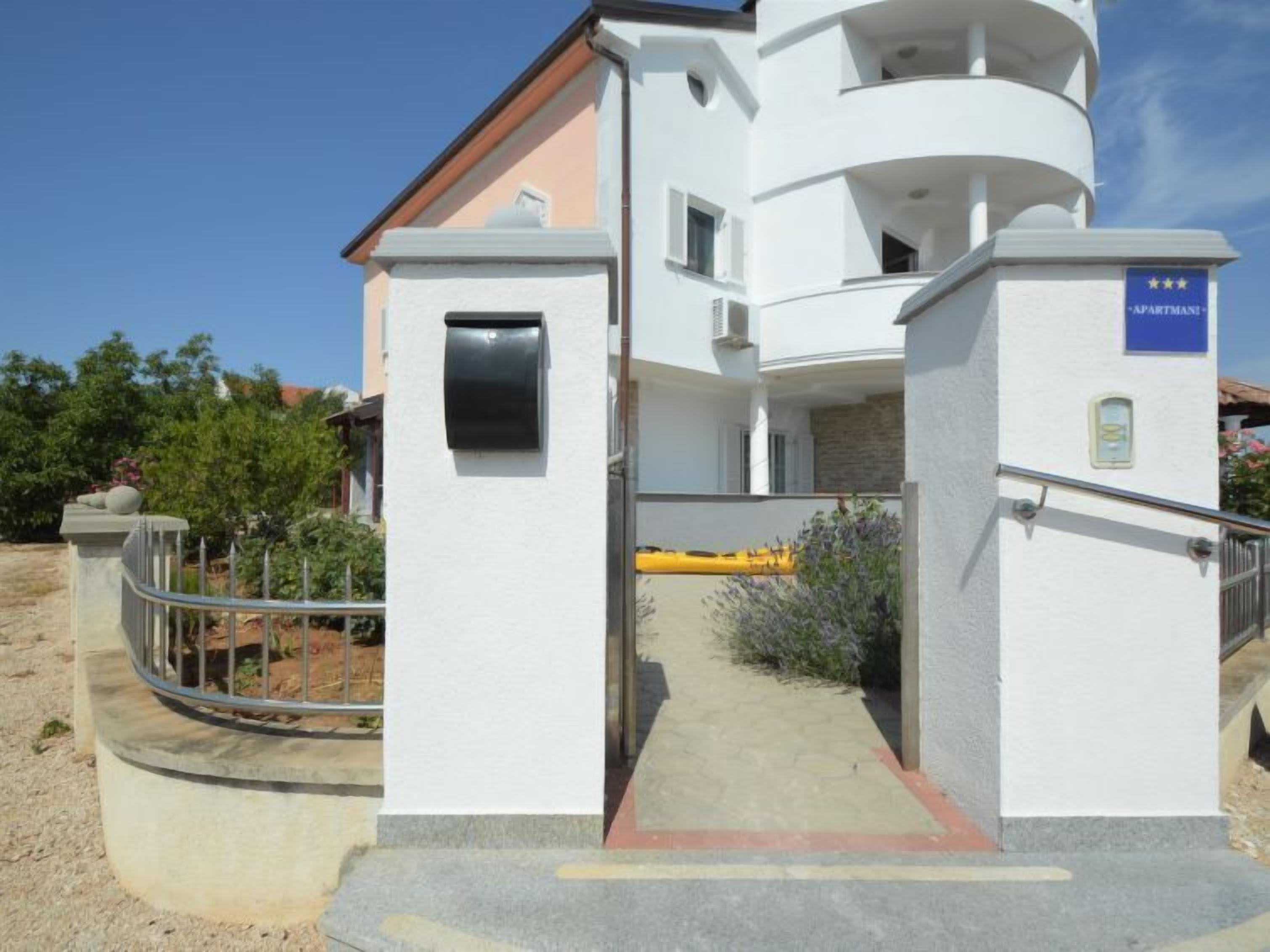 Un immeuble moderne à la façade blanche, avec une boîte aux lettres et une enseigne indiquant qu’il s’agit d’un immeuble d’appartements.