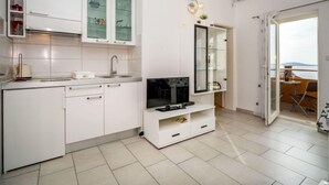 Una cucina moderna con mobili bianchi, forno integrato e zona pranzo con vista sul mare.