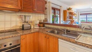 Una cocina con armarios de madera, encimera de granito, horno empotrado, lavavajillas y ventana con vistas.