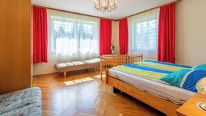 A bedroom with a wooden bed, a bench, a table, and a chandelier. - Apartment Pacher by Interhome (Gallizien)