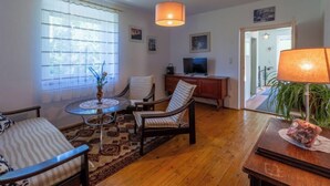 A cozy living room with a round coffee table, two striped armchairs, a wooden cabinet, and a television. - Apartment Pacher by Interhome (Gallizien)