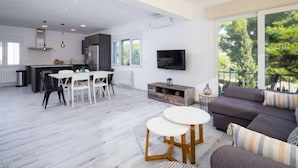 A modern living space with a dining area, kitchen, and a balcony with a view of trees. - Casa Encinas by Interhome (Moraira)