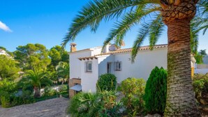 A white villa with a tiled roof, surrounded by lush greenery and a stone pathway. - Casa Encinas by Interhome (Moraira)