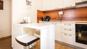Une cuisine moderne avec des meubles blancs, une cuisinière noire et une machine à café.