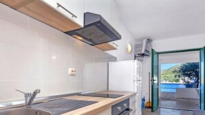 A modern kitchen with a wooden countertop, stainless steel sink, and white cabinetry. - Apartment Rubin by Interhome (Hvar/Pokrivenik)