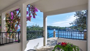 A balcony with a view of a lake and mountains, a table with a vase of flowers, and a chair. - Apartment Rubin by Interhome (Hvar/Pokrivenik)