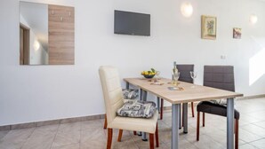 A dining area with a table, chairs, a TV mounted on the wall, and a mirror. - Apartment B&B by Interhome (Medulin/Ližnjan)