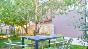 An outdoor seating area with a table and four chairs, surrounded by greenery and a stone wall. - Apartment B&B by Interhome (Medulin/Ližnjan)