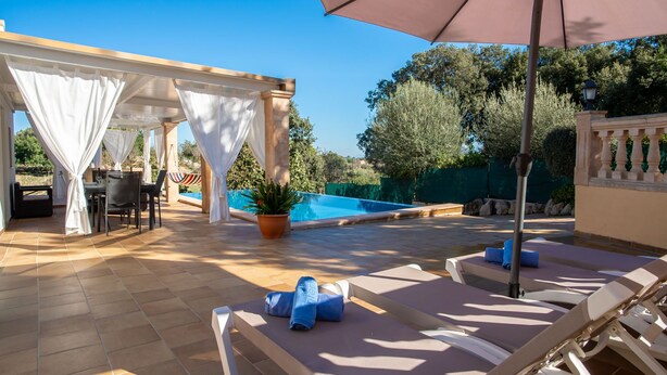 Un espace extérieur ensoleillé doté d’une piscine, de chaises longues et d’un coin salon abrité.
