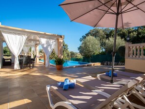 A sunlit outdoor area with a pool, lounge chairs, and a covered seating area. - Can Bernat by Interhome (Biniamar)
