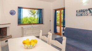 Una habitación con una mesa de comedor, un sofá blanco, una ventana con cortinas, un reloj de pared y un letrero que dice 'CARGO 555'.