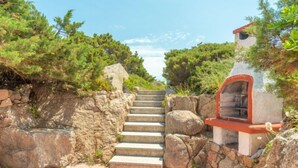 Una escalera de piedra que lleva a un edificio con techo rojo, rodeado de follaje.