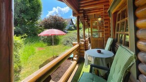 Una baita di legno con un portico, un tavolo e delle sedie.