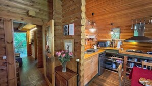 Interno rustico di una baita con arredamento in legno, angolo cottura e zona pranzo.