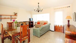 A cozy living room with a dining table, chairs, a sofa, and a TV.